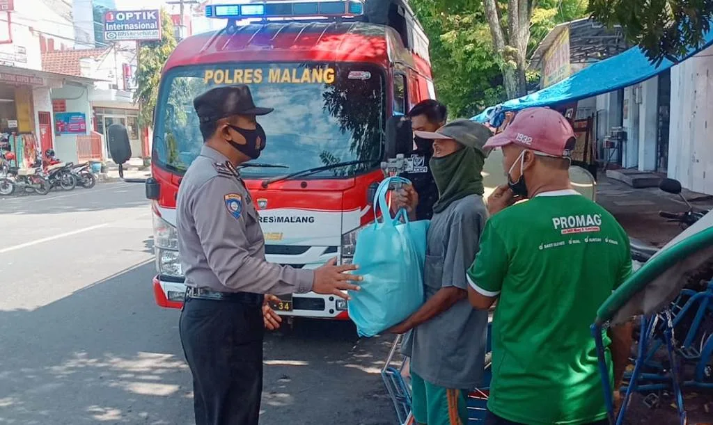Anggota Polres Malang saat membagikan sembako kepada warga tidak mampu, Jum'at Berkah