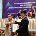 Ketua lama PDFI Dr. dr. Ade Firmansyah Sugiharto, Sp. F.M(K) menyerahkan tonggak estafet kepemimpinan kepada ketua terpilih PDFMI periode 2022-2025, Prof Dr. dr. Dedi Afandi, Sp.F.M Subsp.E.M(K), MM, MARS