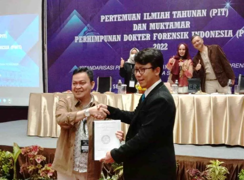 Ketua lama PDFI Dr. dr. Ade Firmansyah Sugiharto, Sp. F.M(K) menyerahkan tonggak estafet kepemimpinan kepada ketua terpilih PDFMI periode 2022-2025, Prof Dr. dr. Dedi Afandi, Sp.F.M Subsp.E.M(K), MM, MARS
