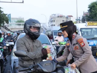 Salah satu Polisi Wanita (Polwan) saat membagikan bunga dan snack kepada pengendara sepada motor