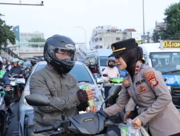 Salah satu Polisi Wanita (Polwan) saat membagikan bunga dan snack kepada pengendara sepada motor