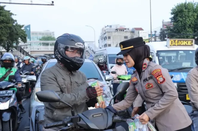 
Salah satu Polisi Wanita (Polwan) saat membagikan bunga dan snack kepada pengendara sepada motor